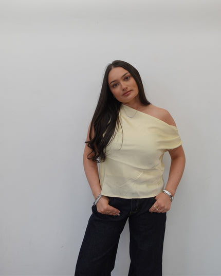 Woman wearing a light-colored top and dark pants on a plain background