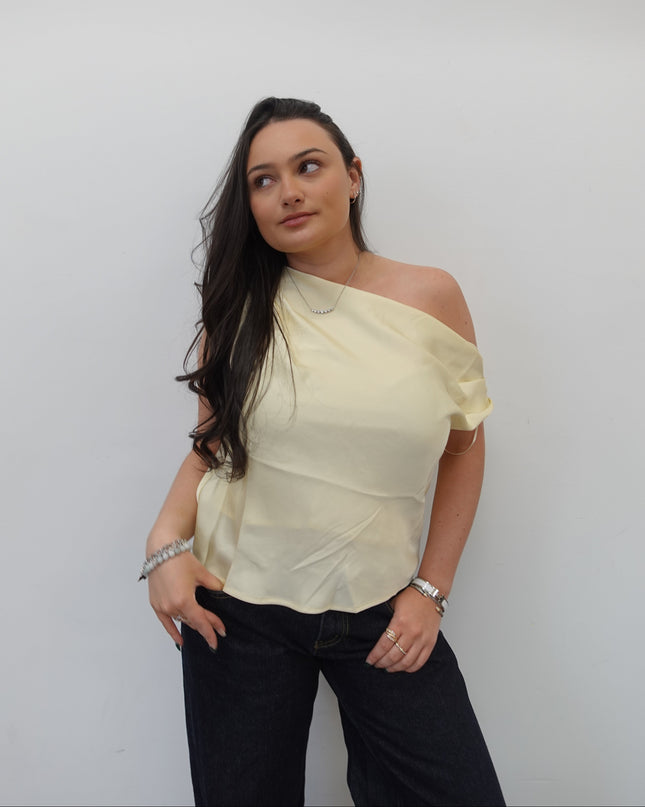 Woman wearing a light-colored blouse and dark pants on a white background